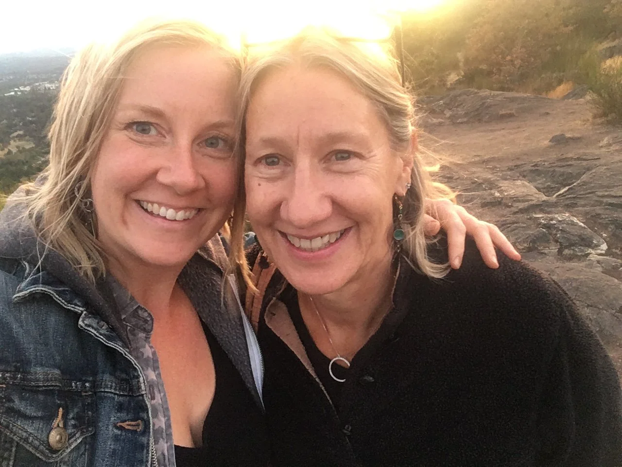Juliana and her mum smiling together at sunset