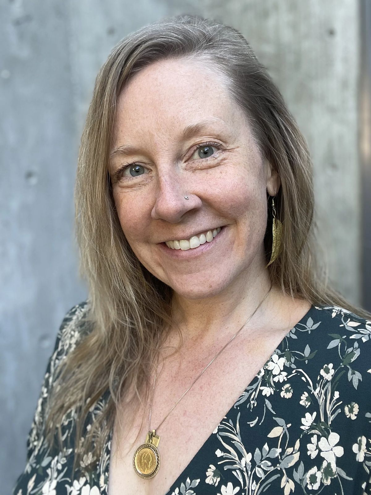 Juliana Christine smiling, wearing a gold pendant necklace.