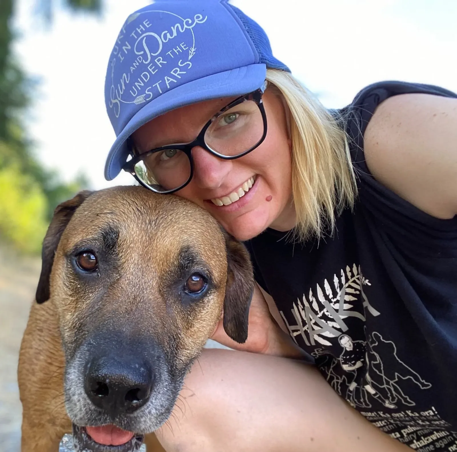Erica smiling and cuddling her dog outdoors
