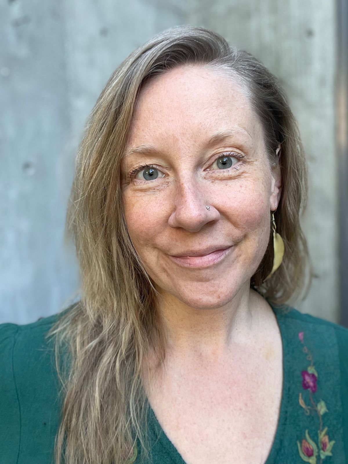 Juliana Christine, smiling softly, in a green embroidered top