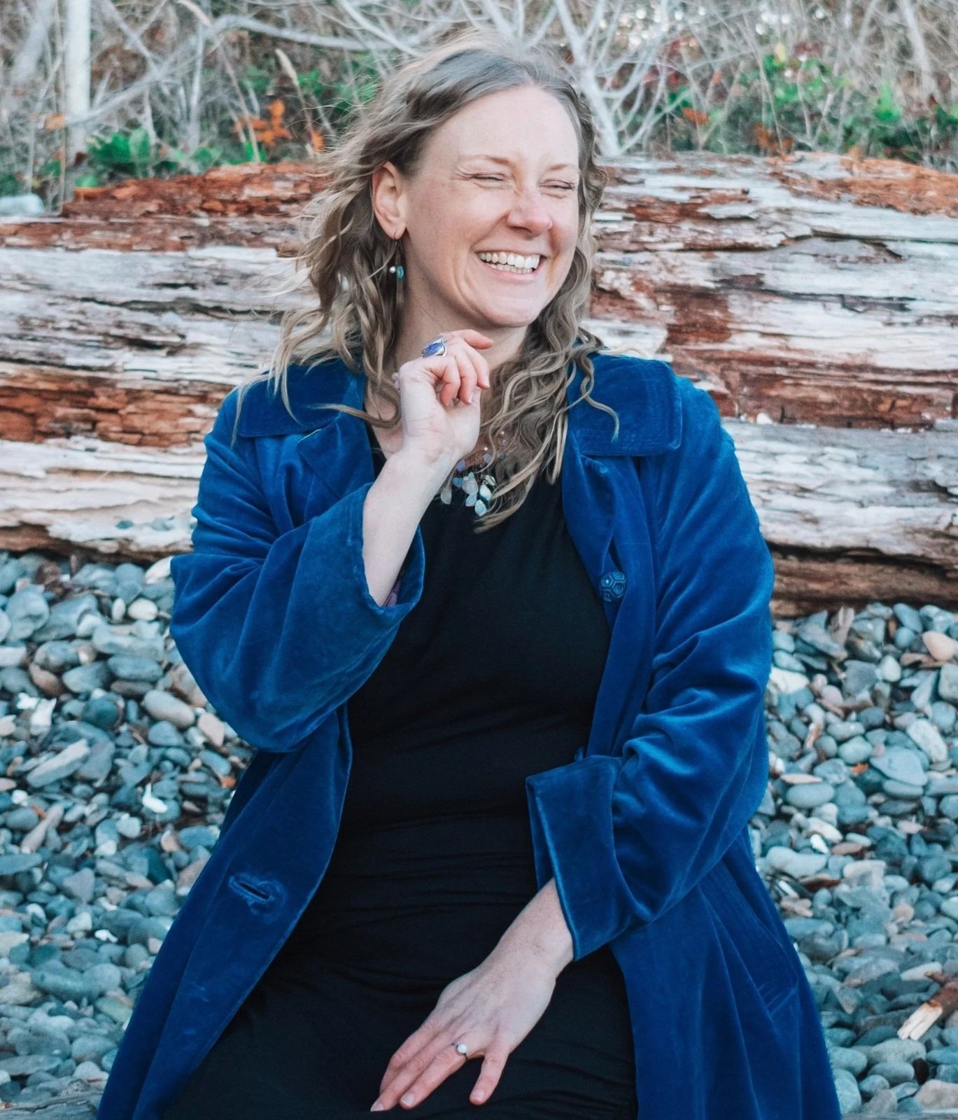 Juliana smiling with eyes closed, sitting on rocks