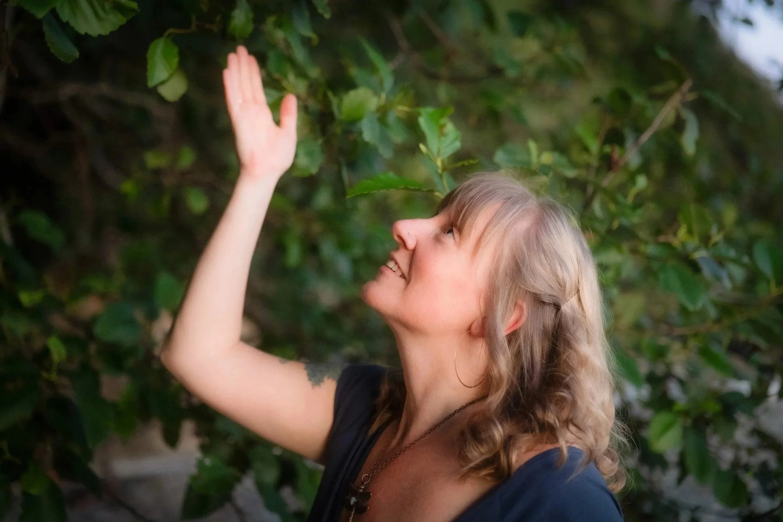 Juliana smiling and reaching toward green leaves