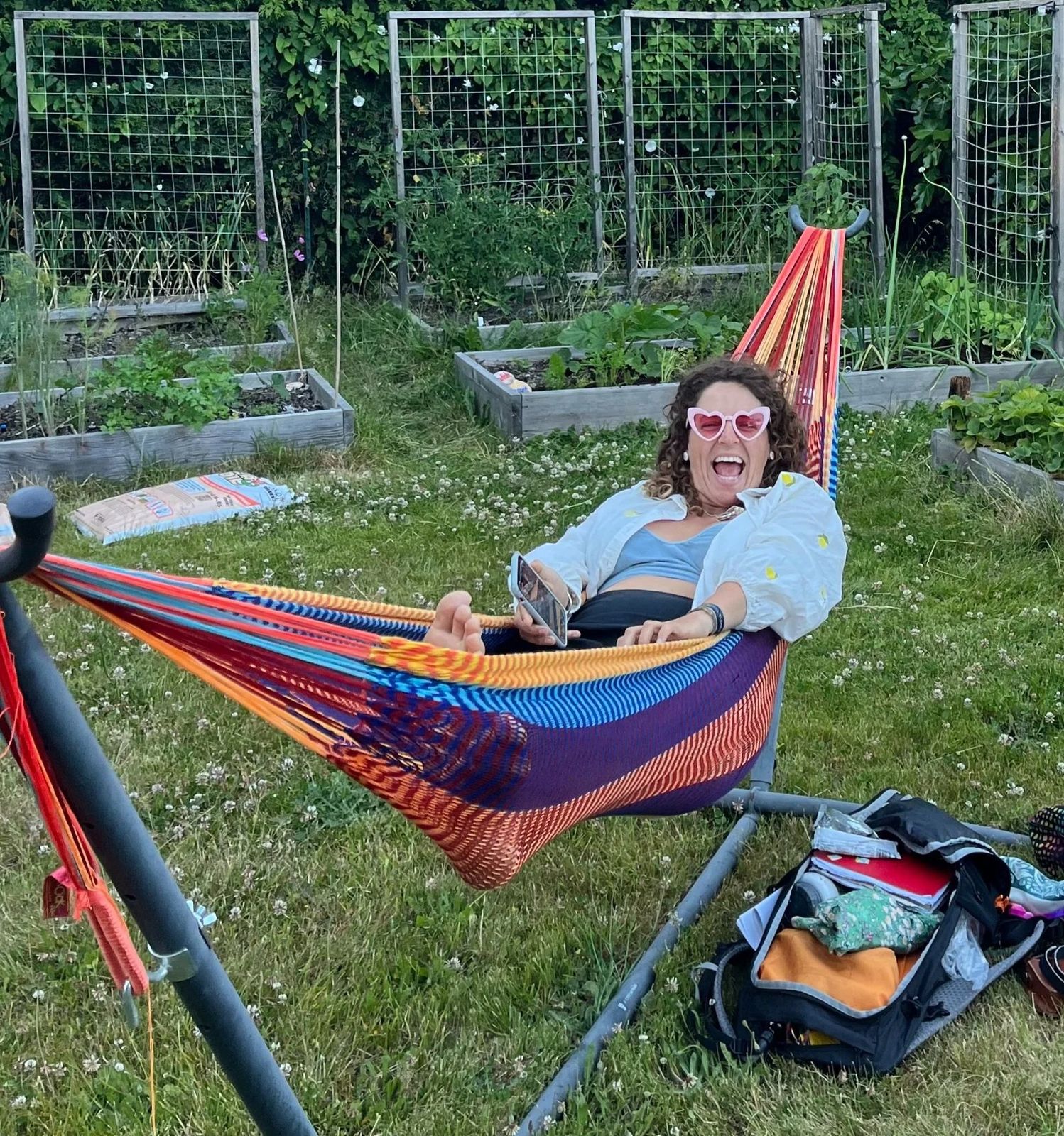 Lucy laughing in a colourful hammock in a garden